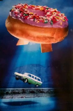 a donut with sprinkles is floating in the air next to a car