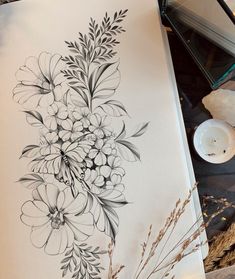 a black and white drawing of flowers on a piece of paper next to a candle