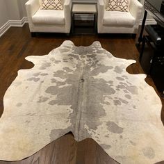 a living room with two white chairs and a cow hide rug in the middle of the floor