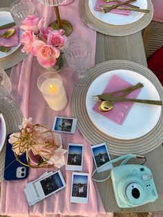 the table is set with pink and white plates, silverware, photos, and candles