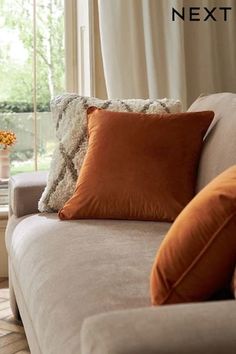 a couch with pillows on it in front of a window and the words next to it