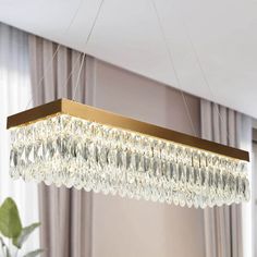 a chandelier hanging from the ceiling in a living room with curtains and windows