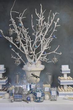 a table topped with lots of cakes and desserts next to a vase filled with branches