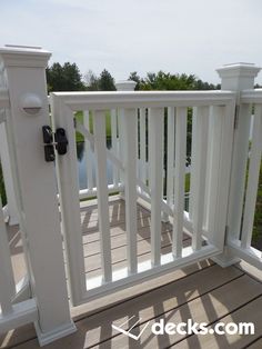 a wooden deck with white railings and black knobs on the top part of it