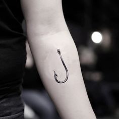 a black and white photo of a person's arm with a fishing hook tattoo on it