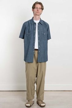 An updated version of the garage shirt - a fun take on a classic american work shirt with western-inspired details    cut from a summer weight chambray cloth - a plain weave fabric that has been used for hundreds of years in workwear garments    because of its typically fine weave it is great for regulating heat and keeping its wearer cool    —    100% cotton    regular fit    seven pearl snap fastener front    two pearl snap fastener pockets    longer at the back    one collar button    top sti Garage Shirt, Evolution Of Fashion, Weave Fabric, Universal Works, Blue Flats, Snap Fasteners, Work Shirt, Mens Button Up, Button Top