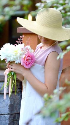 a woman in a white dress and hat holding flowers