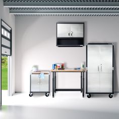 a kitchen with white walls and cabinets in the center, including a microwave on top of a table