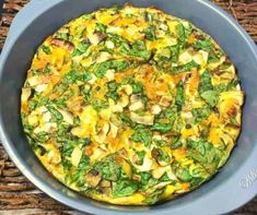 an omelet with spinach and mushrooms in a blue bowl on a wicker place mat