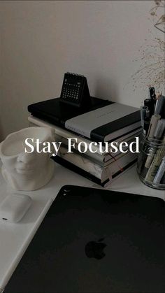 an apple computer sitting on top of a white desk next to a stack of books