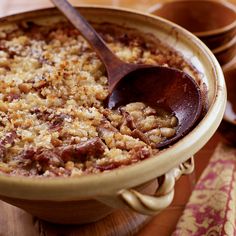 a wooden spoon is in a bowl filled with rice and other food on a table