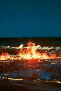 a fire hydrant in the middle of an ocean with water splashing around it