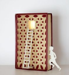 an open book with a lit candle in the shape of a ladder on top of it