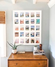 a wooden dresser topped with a potted plant next to a wall mounted art piece