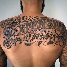 the back of a man's upper body with tattoos on it