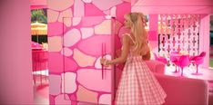 a barbie doll standing in front of a pink room