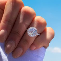 a woman's hand holding an engagement ring with a diamond center in the middle