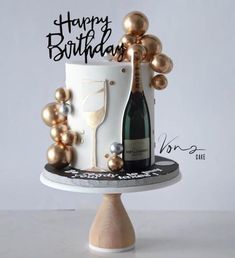 a birthday cake with a bottle of champagne on top and balloons in the air around it