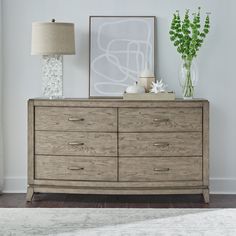 a wooden dresser with two vases and a painting on it's sideboard