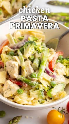 chicken pasta prima primavera in a white bowl with tomatoes and asparagus