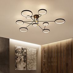 a modern ceiling light with circular lights in a living room or dining room, along with paintings on the wall