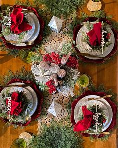 the table is set for christmas dinner with red napkins and greenery on it