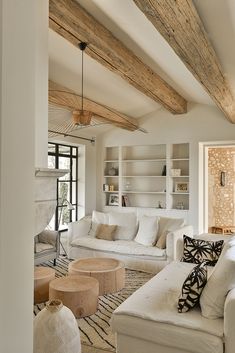 a living room filled with white furniture and wooden beamed ceiling beams in an open floor plan