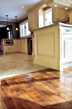 an empty kitchen with wooden floors and white cabinetry on the island in the middle