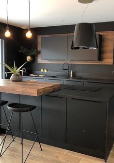 a kitchen with black cabinets and stools next to an island counter top in front of a window