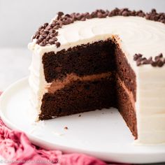 a chocolate cake with white frosting and chocolate chips on the top is cut in half