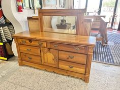 a wooden dresser sitting in front of a mirror on top of a floor next to a wall