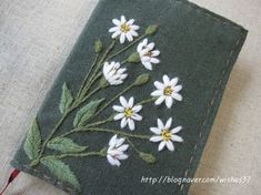 a close up of a piece of cloth with white flowers on it and green leaves