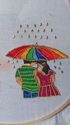 two people under an umbrella with beading on the back of it, in front of a white background