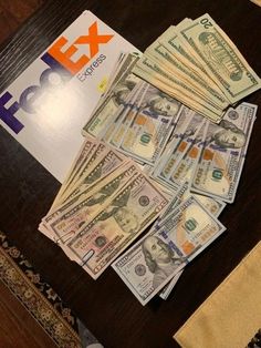 stacks of money sitting on top of a table next to a pile of fedex bills