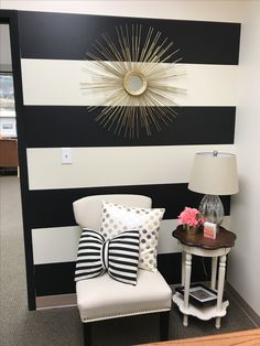 a room with black and white striped walls, a chair and lamp on the side table