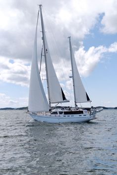 a sailboat sailing on the water under a cloudy sky