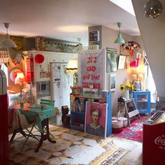 a room filled with furniture and pictures on the wall next to a table in front of a refrigerator