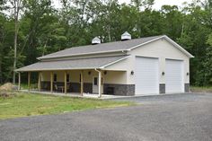 a white garage with two cars parked in front of it and trees behind the garage