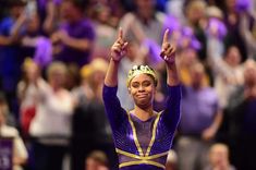 a woman in a purple and gold leotard with her hands up