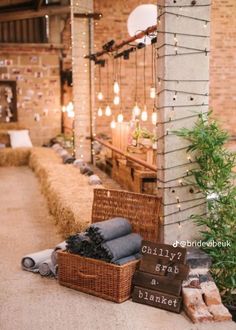 an outdoor area with hay bales and lights hanging from the ceiling, along with two wicker baskets filled with items