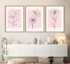 three pink flowers are on the wall above a white dresser and sideboard in this modern living room