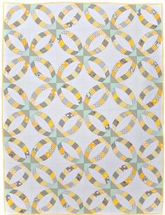 a white quilt with yellow and grey circles on it, in the middle of a square