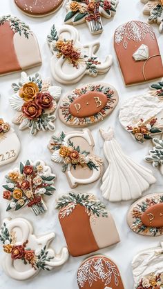 many decorated cookies sitting on top of a white table covered in frosting and flowers