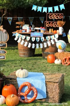 an outdoor birthday party with pumpkins, pretzels and bunting banners on hay bales