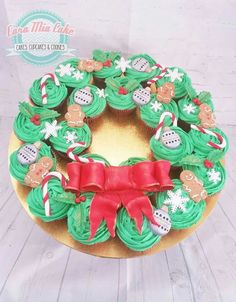 cupcakes decorated with green frosting and red ribbon on top of a cake