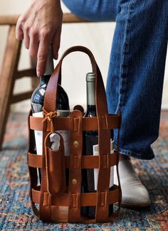 a person sitting on a chair holding a brown bag filled with wine bottles and glasses