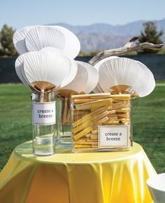 a table topped with bottles filled with wooden sticks and paper fan shaped decorations on top of it