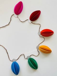 an origami flower is hanging from a string on a white surface with other paper flowers