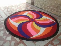 a colorful rug on the ground in front of a brick wall