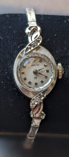 From  ca 1950s, this exquisite 10KT White Gold Lady Hamilton Cocktail Watch defines the glamour of  the era with a delightful mix of diamonds and lovely case and bezel. Crafted in gleaming 10K solid white gold (marked) case and back has beautiful pressed engravings. The original expanding bracelet is a Admiral 10KT filled white gold design.    Wear it with the confidence that you are as distinctive as the watch. This is a one-of-a-kind ladies bracelet and watch which makes a great gift. The 17 J Vintage Evening Diamond Watch With Accents, Vintage White Gold Diamond Watch With Accents, Vintage Diamond Jewelry And Watches With Polished Finish, Vintage Diamond Jewelry With Polished Finish, Vintage Diamond Watch With Polished Finish For Wedding, Vintage Round Diamond Jewelry And Watches, Vintage Wedding Watches With Diamond Accents, Vintage Diamond Jewelry And Watches For Gift, Vintage Diamond Jewelry And Watches As Gifts